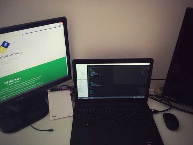 Local de trabalho, com 1 monitor, 1 notebook e uma TV